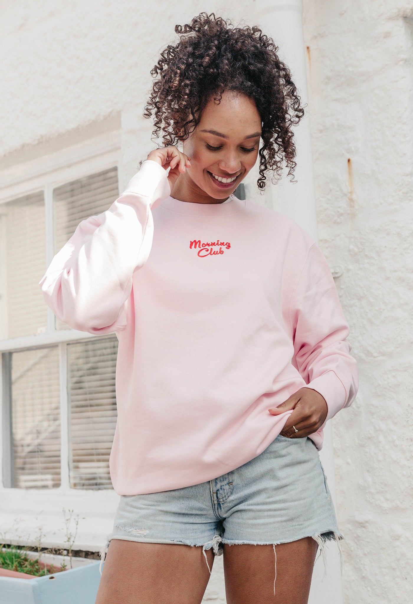 A lady wearing a printed breakfast fry-up graphic style sweatshirt, set by the sea.