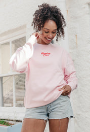 A lady wearing a printed breakfast fry-up graphic style sweatshirt, set by the sea.