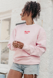 A lady wearing a printed breakfast fry-up graphic style sweatshirt, set by the sea.