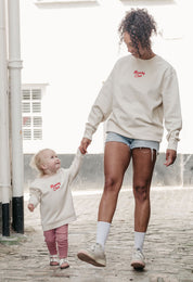 A lady wearing a printed breakfast fry-up graphic style sweatshirt, set by the sea.