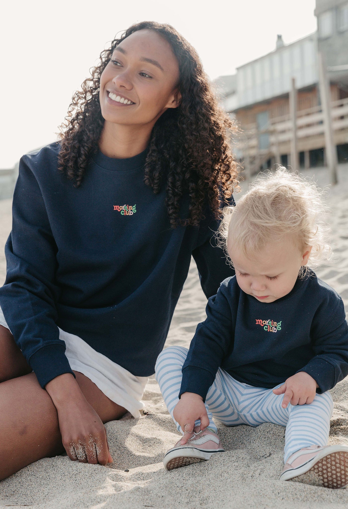 Lady wearing a plain embroidered sweatshirt, and its set on the beach.