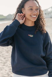 Lady wearing a plain embroidered sweatshirt, and its set on the beach.