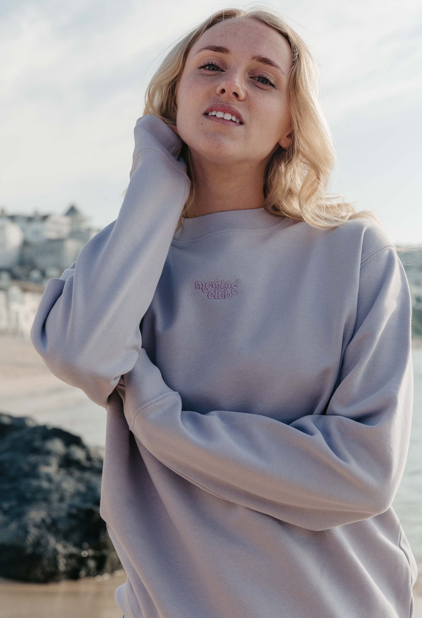 Lady wearing a plain embroidered sweatshirt, and its set on the beach.