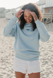 Lady wearing a plain embroidered sweatshirt, and its set on the beach.