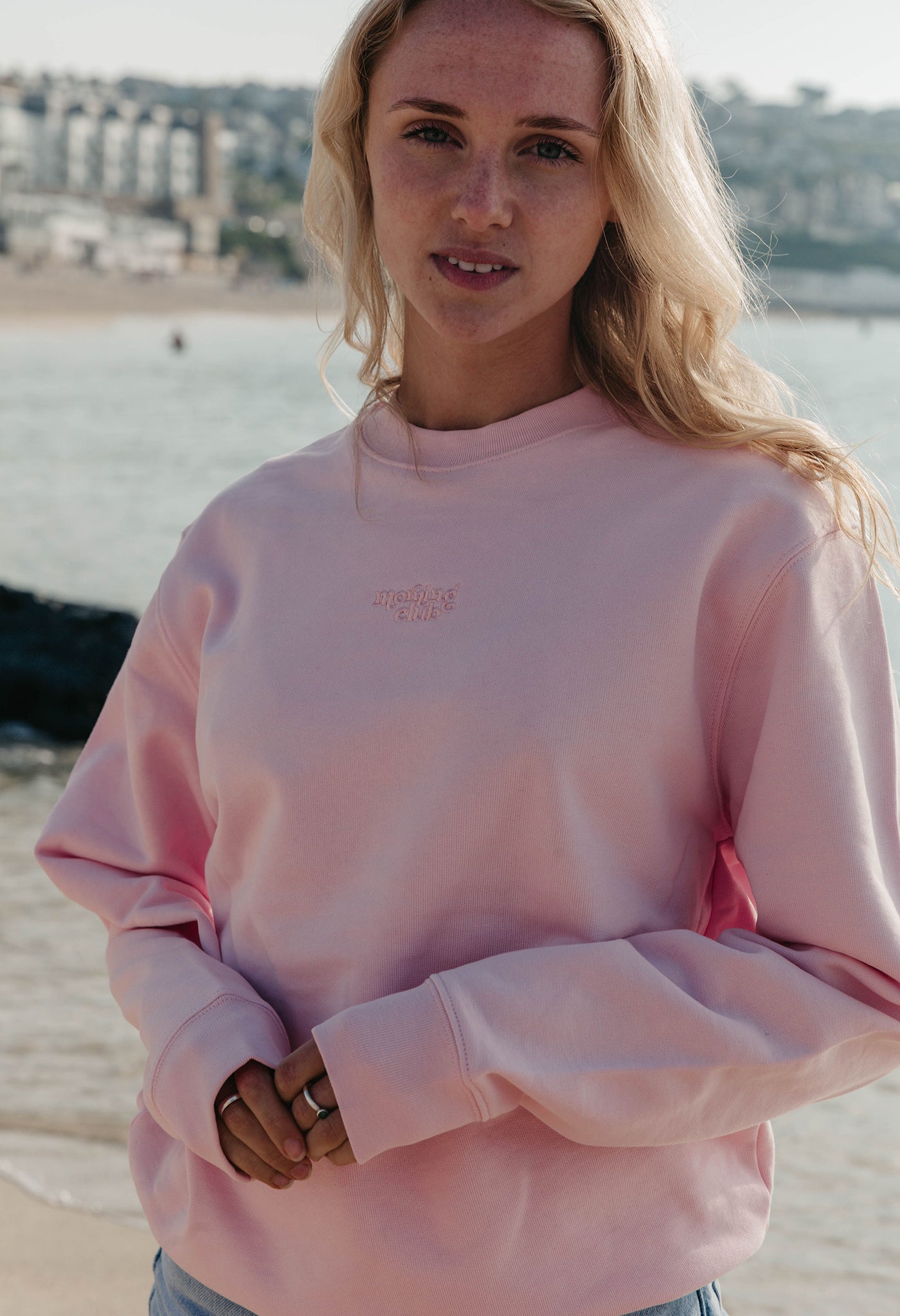 Lady wearing a plain embroidered sweatshirt, and its set on the beach.