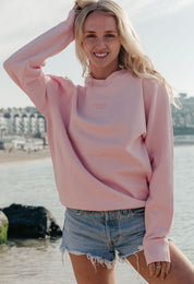 Lady wearing a plain embroidered sweatshirt, and its set on the beach.