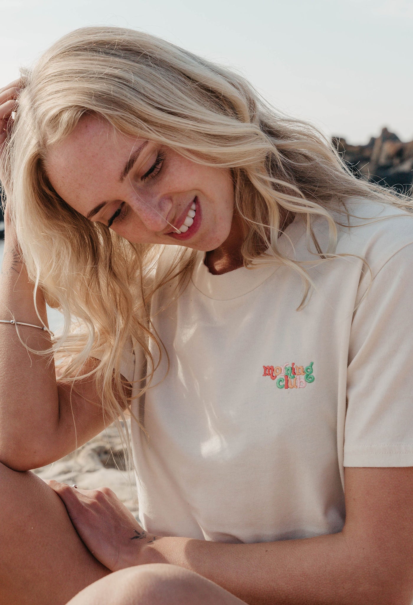 Lady wearing a plain embroidered t-shirt, and its set on the beach.