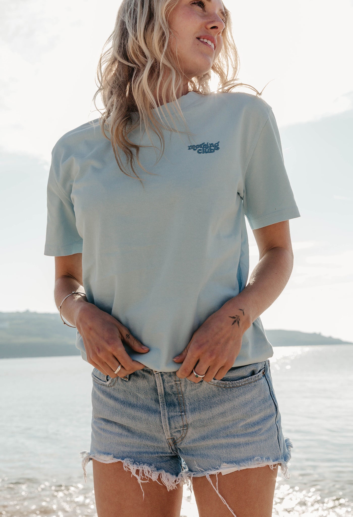 Lady wearing a plain embroidered t-shirt, and its set on the beach.