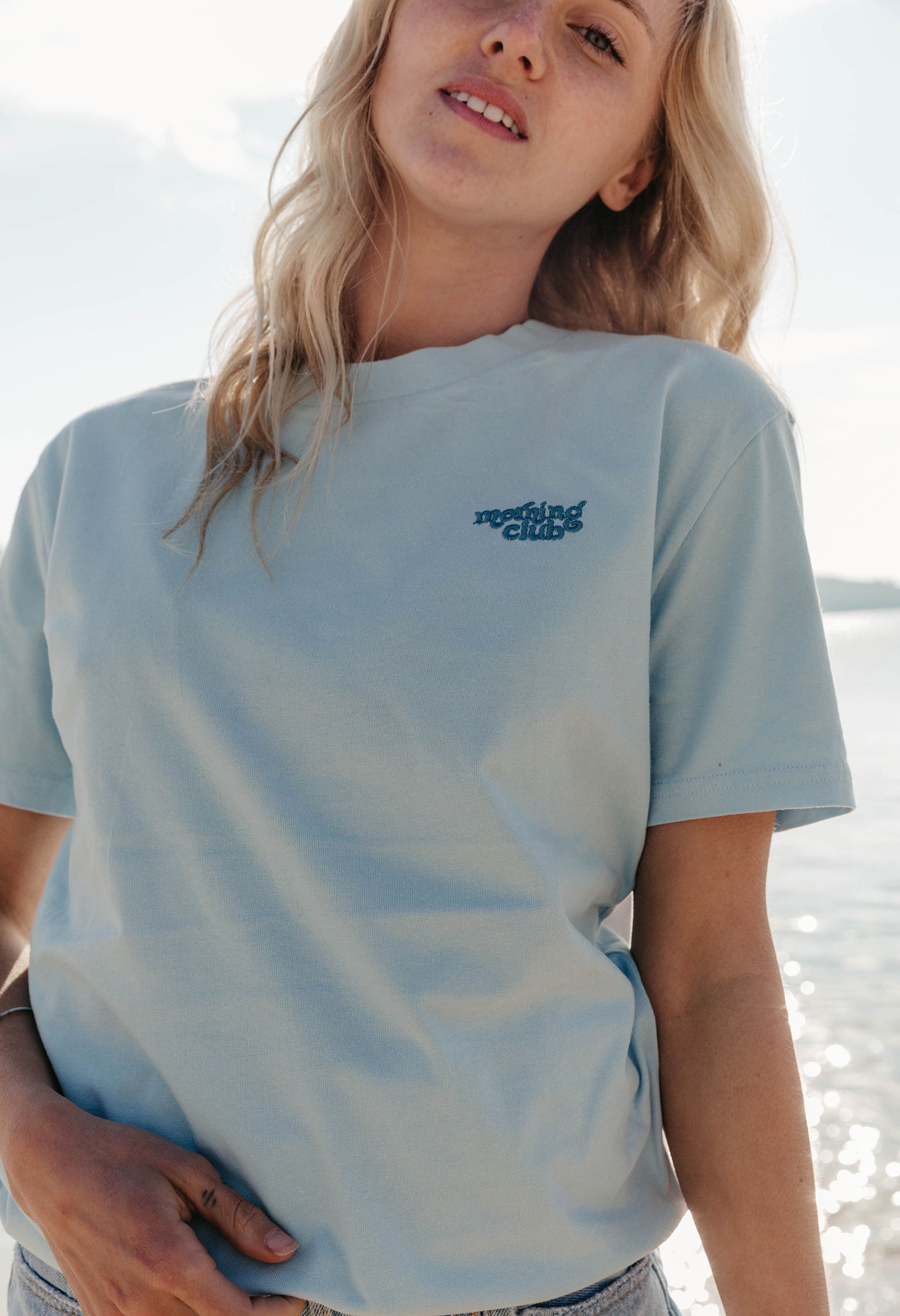 Lady wearing a plain embroidered t-shirt, and its set on the beach.