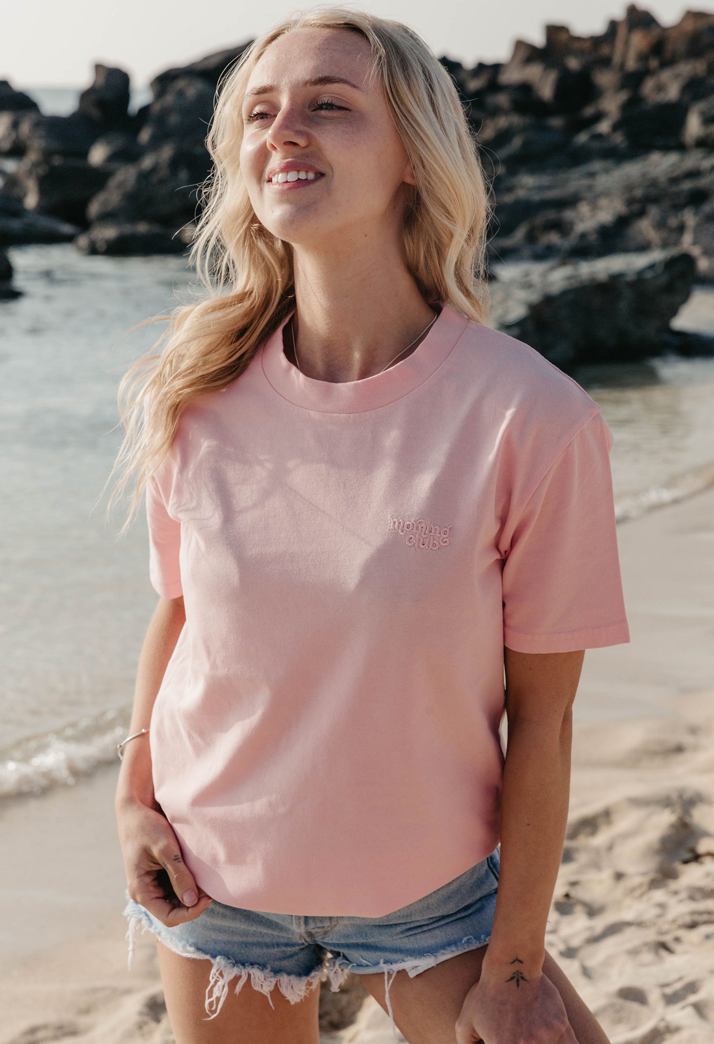 Lady wearing a plain embroidered t-shirt, and its set on the beach.