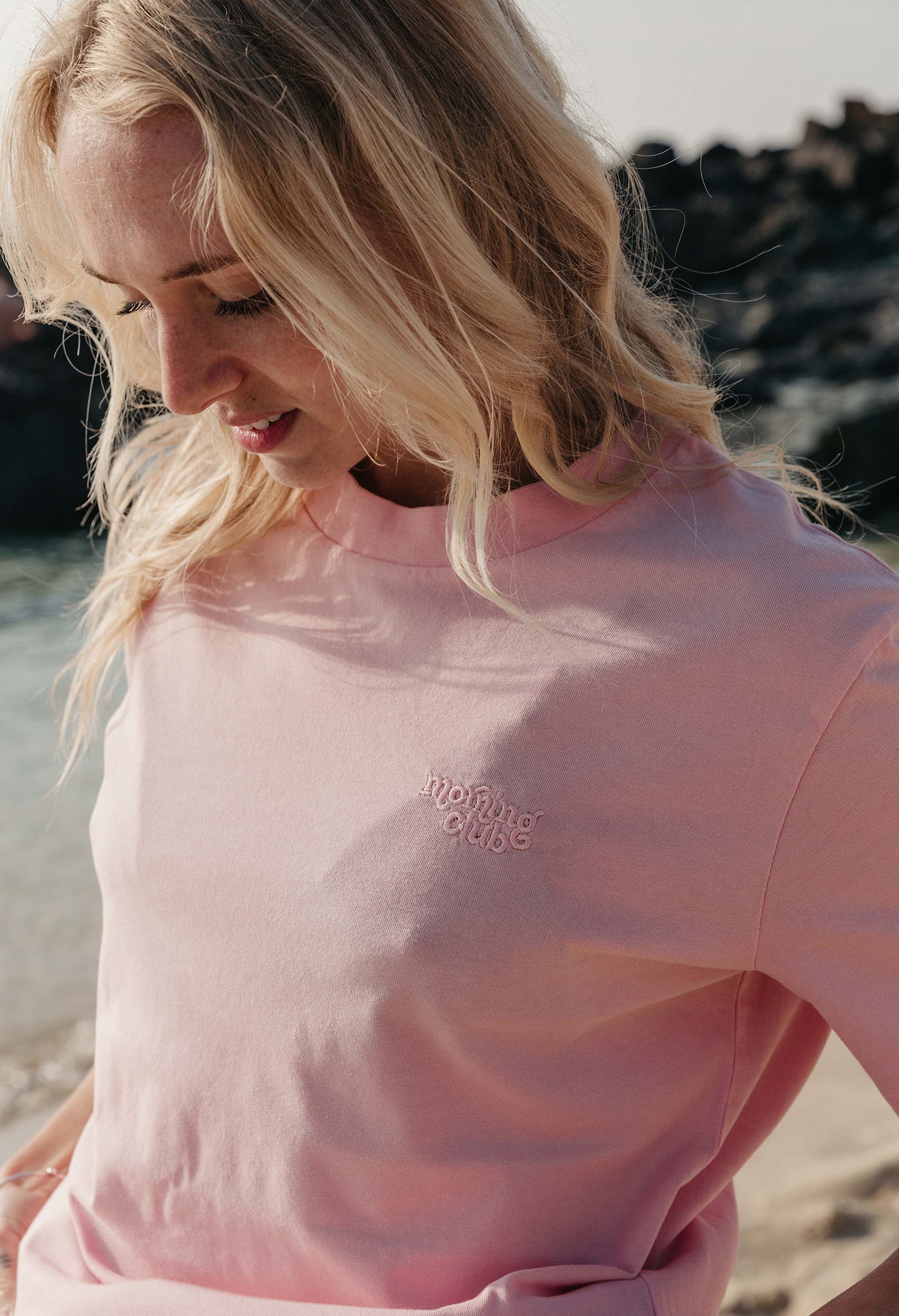 Lady wearing a plain embroidered t-shirt, and its set on the beach.