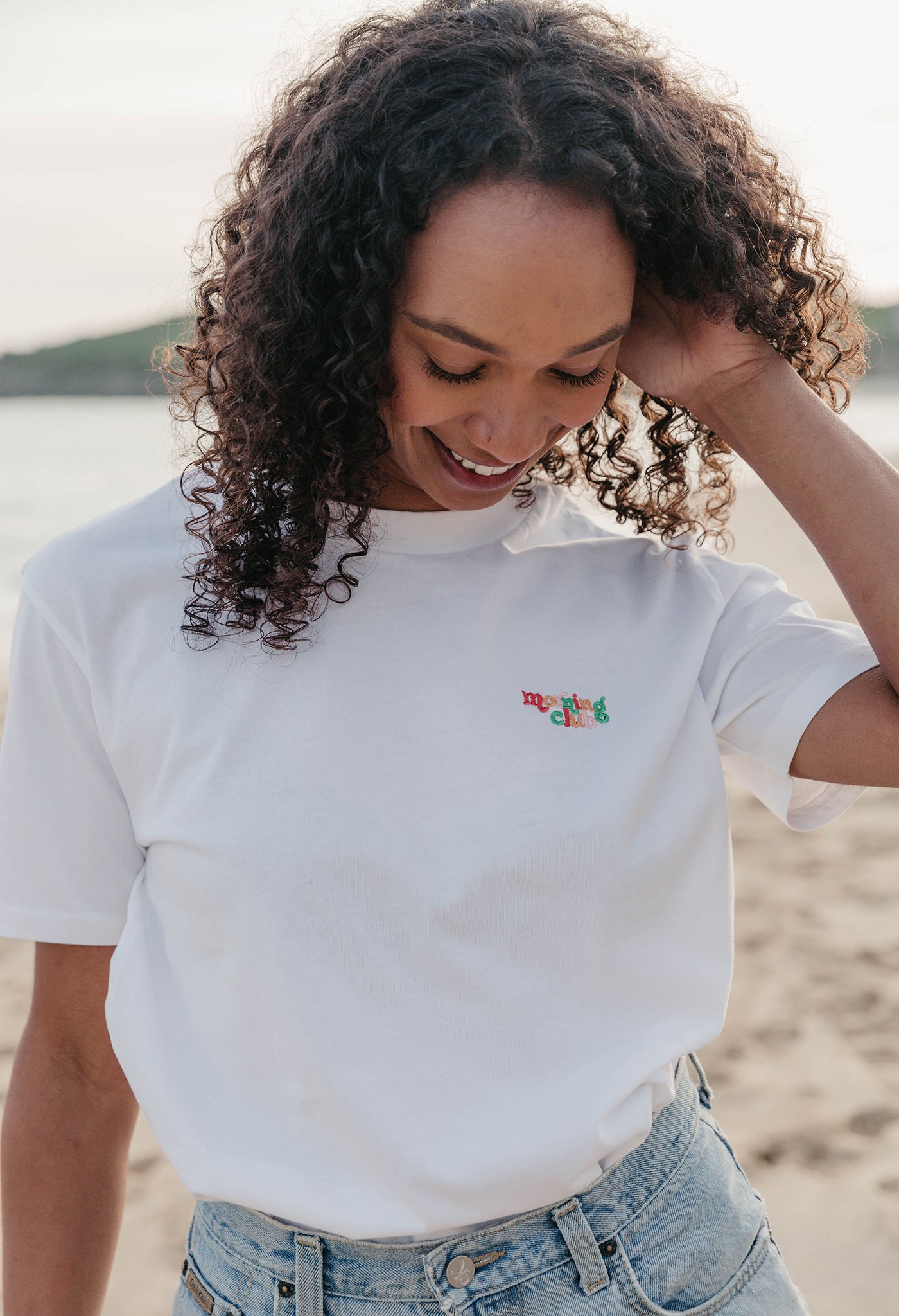 Lady wearing a plain embroidered t-shirt, and its set on the beach.