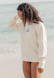 Lady wearing a printed sweatshirt, that says into the wilderness, and its set on the beach.