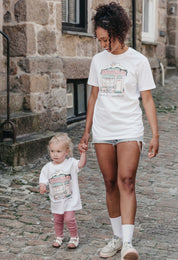 A lady and baby wearing a white printed graphic t-shirt, Morning Club Cafe, set in a town.