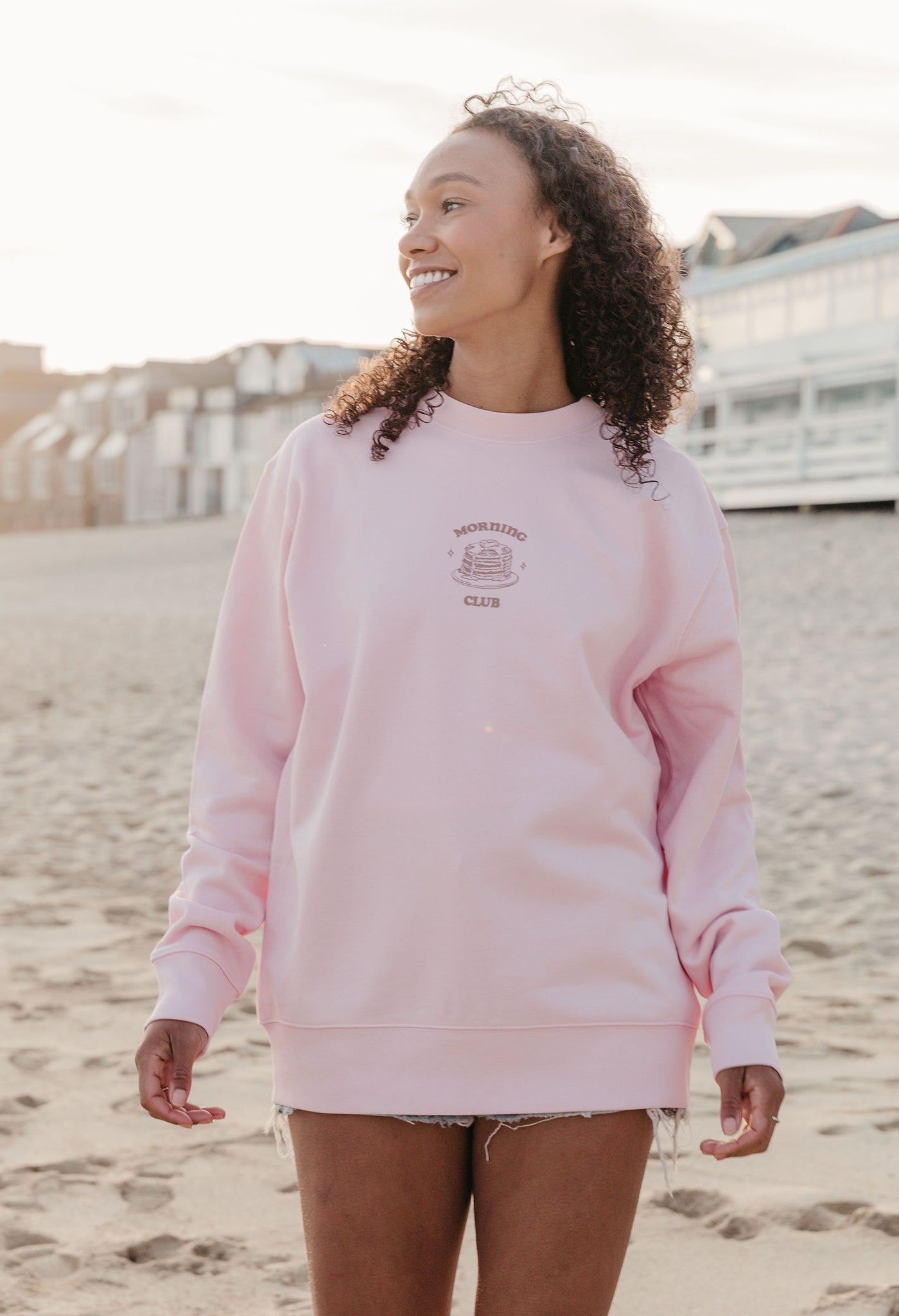 A lady wearing a printed pancake style printed sweatshirt, set by the sea.