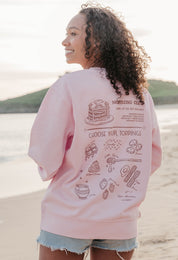 A lady wearing a printed pancake style printed sweatshirt, set by the sea.