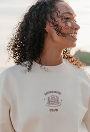 A lady wearing a printed pancake style printed sweatshirt, set by the sea.