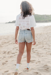 A lady wearing a white printed graphic t-shirt, with a illustration of a pancakes and toppings.