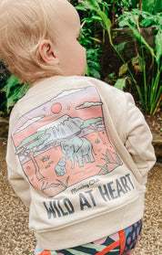 Toddler wearing a printed sweatshirt, that says wild at heart, featuring an elephant print.