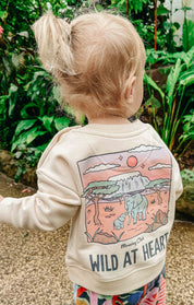 Toddler wearing a printed sweatshirt, that says wild at heart, featuring an elephant print.