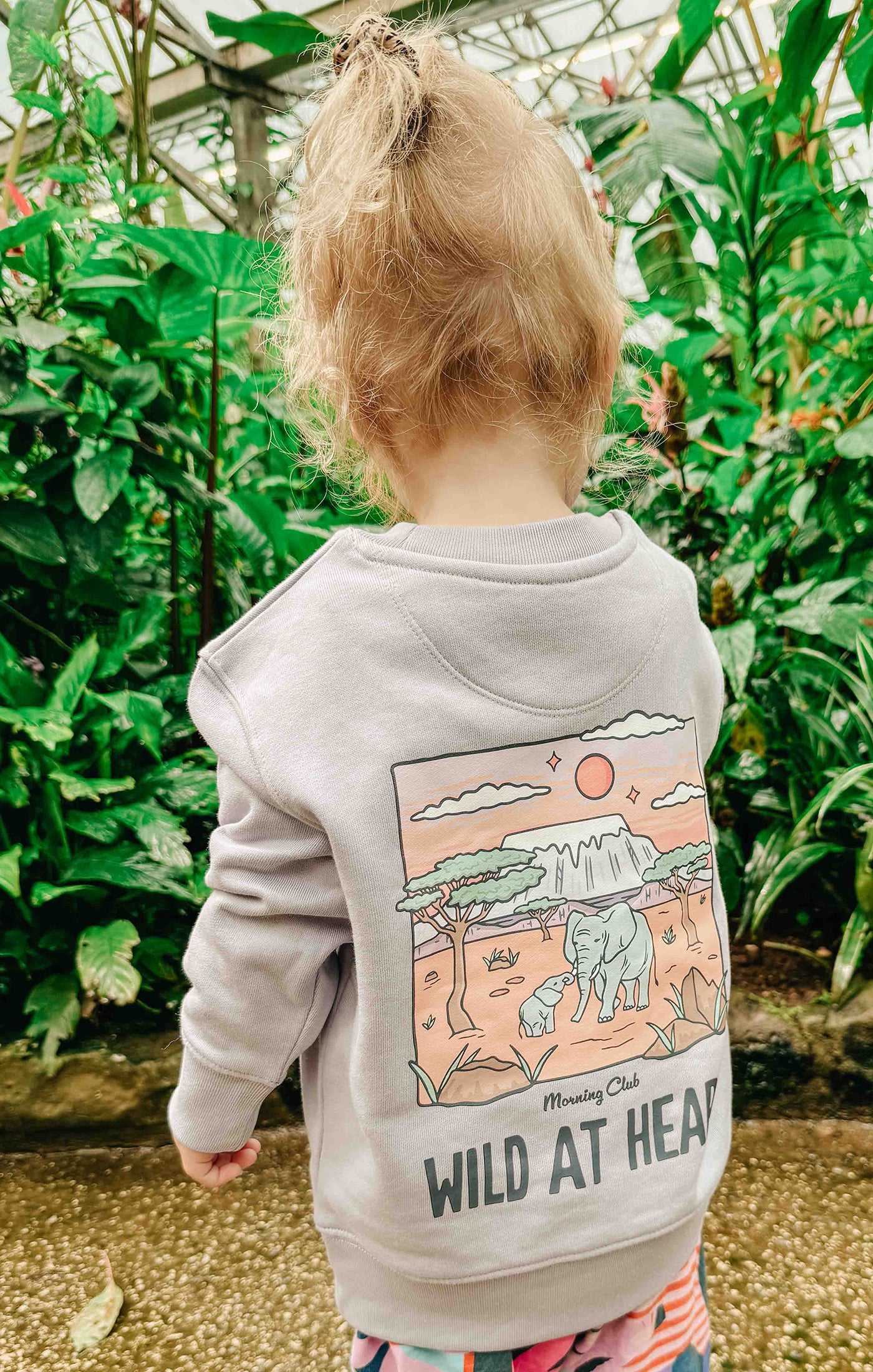 Toddler wearing a printed sweatshirt, that says wild at heart, featuring an elephant print.