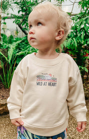 Toddler wearing a printed sweatshirt, that says wild at heart, featuring an elephant print.