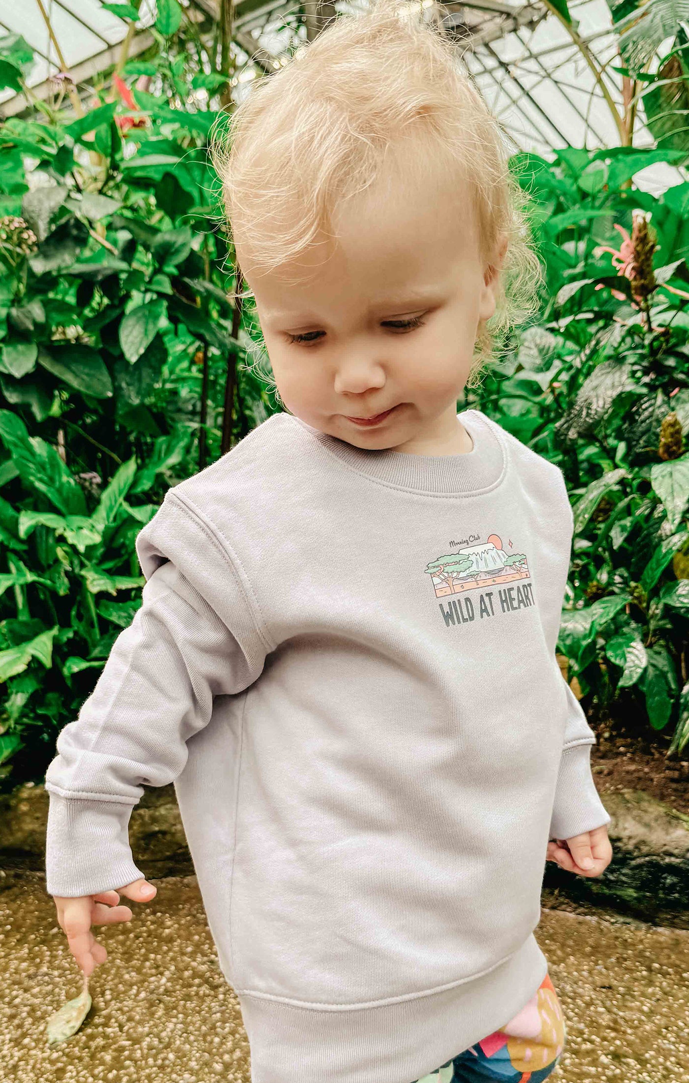 Toddler wearing a printed sweatshirt, that says wild at heart, featuring an elephant print.