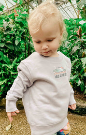 Toddler wearing a printed sweatshirt, that says wild at heart, featuring an elephant print.