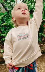 Toddler wearing a printed sweatshirt, that says wild at heart, featuring an elephant print.