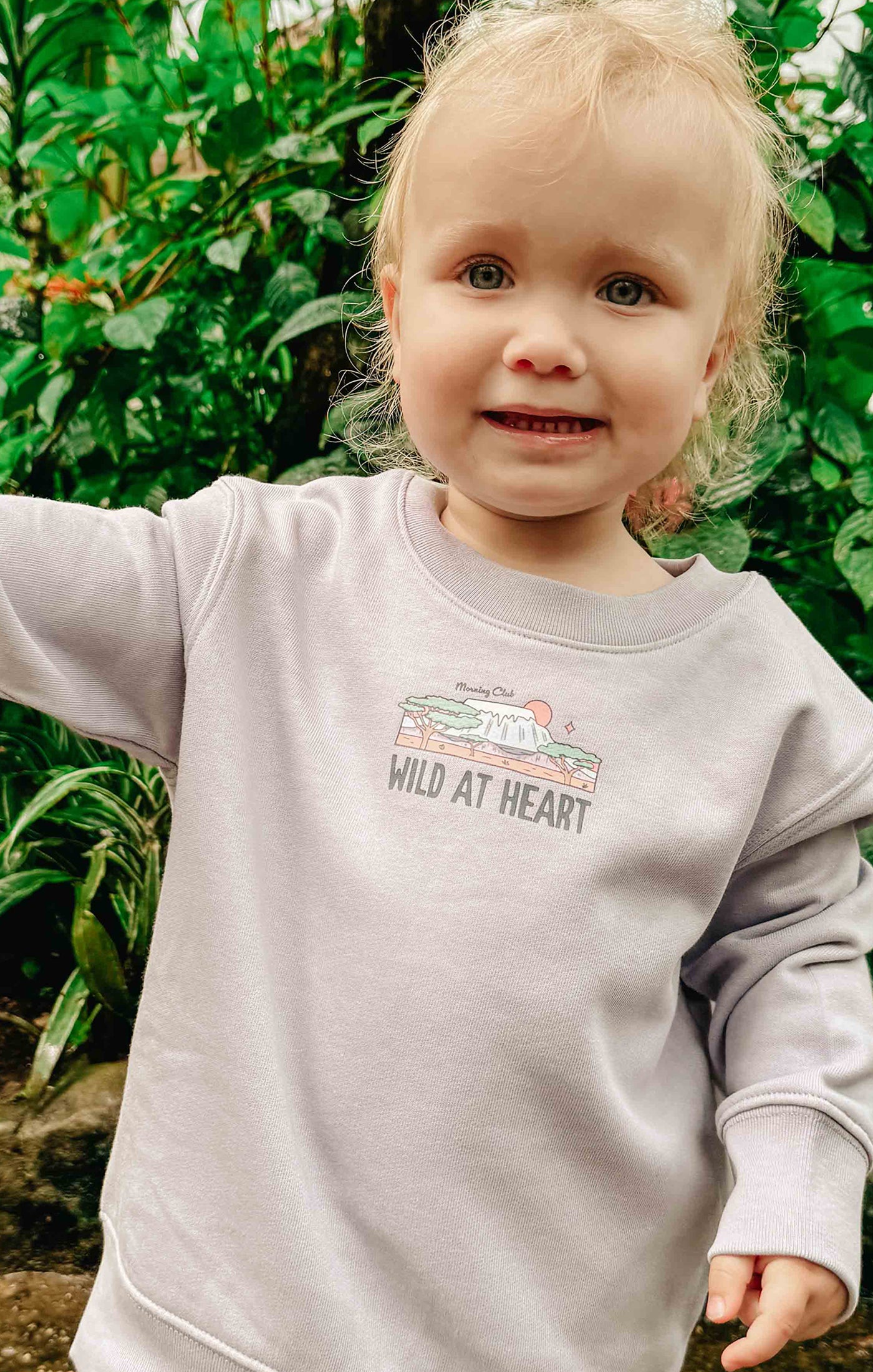 Toddler wearing a printed sweatshirt, that says wild at heart, featuring an elephant print.