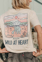 A lady wearing a natural printed graphic t-shirt, that says wild at heart, set by the beach.